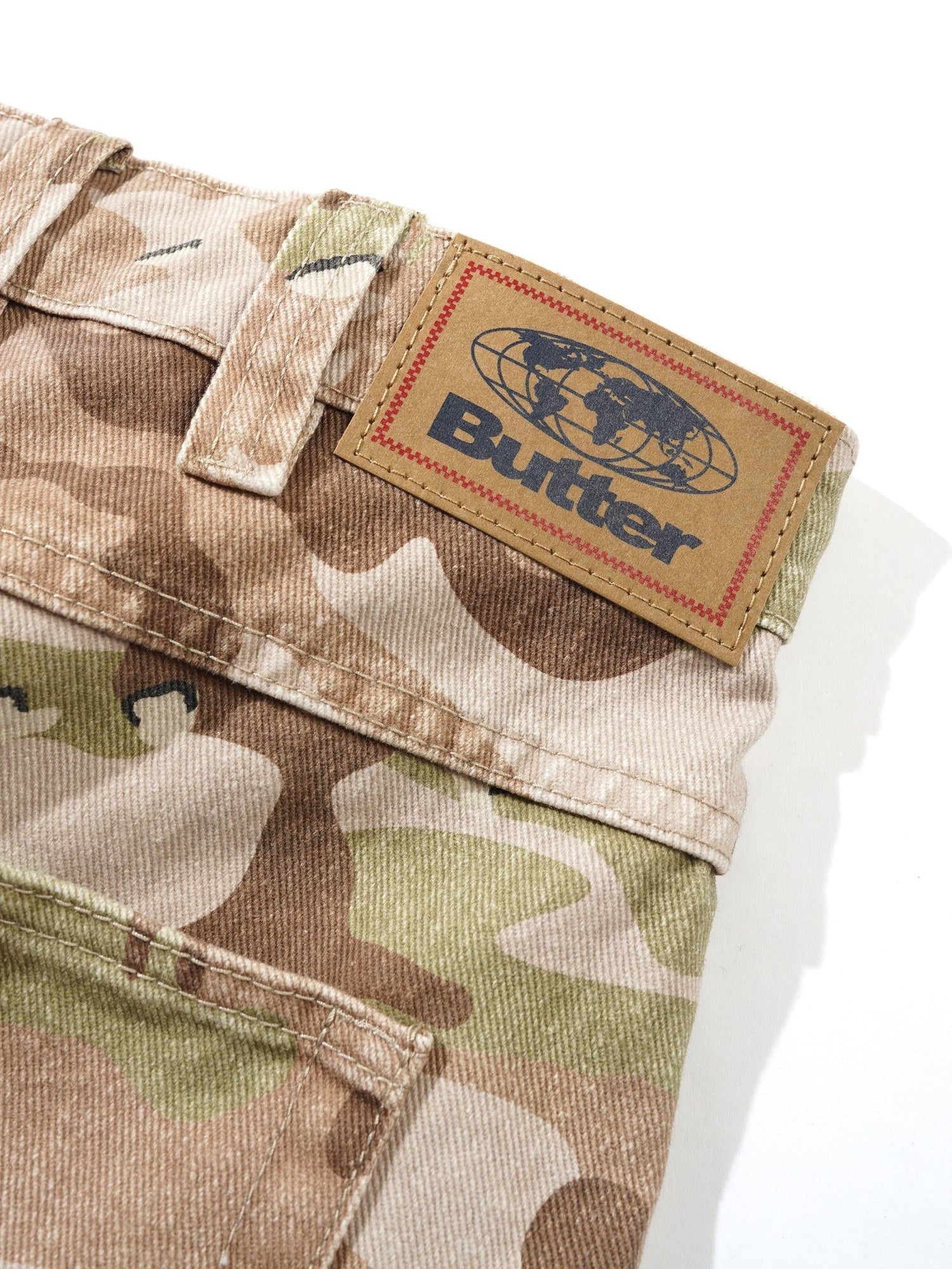 Camouflage pants with a visible 'Butter' brand label on a white background