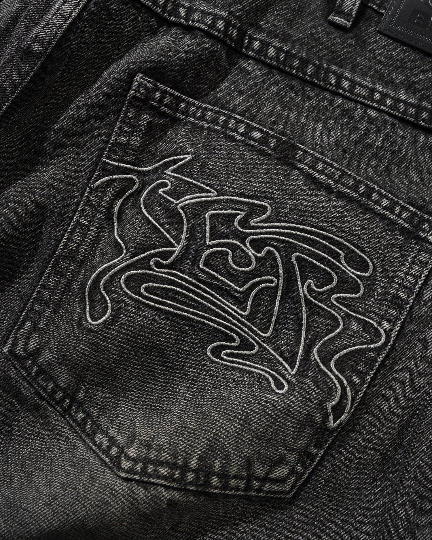Close-up of a black denim pocket with a white embroidered design on a dark background