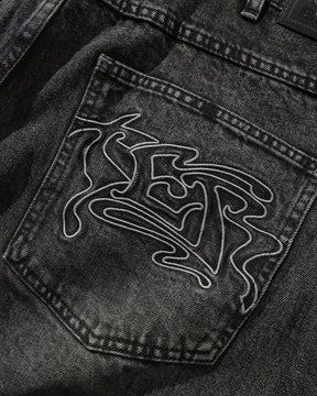 Close-up of a black denim pocket with a white embroidered design on a dark background