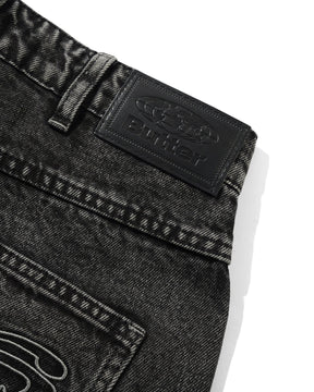 Close-up of black denim jeans with a brand logo on a white background