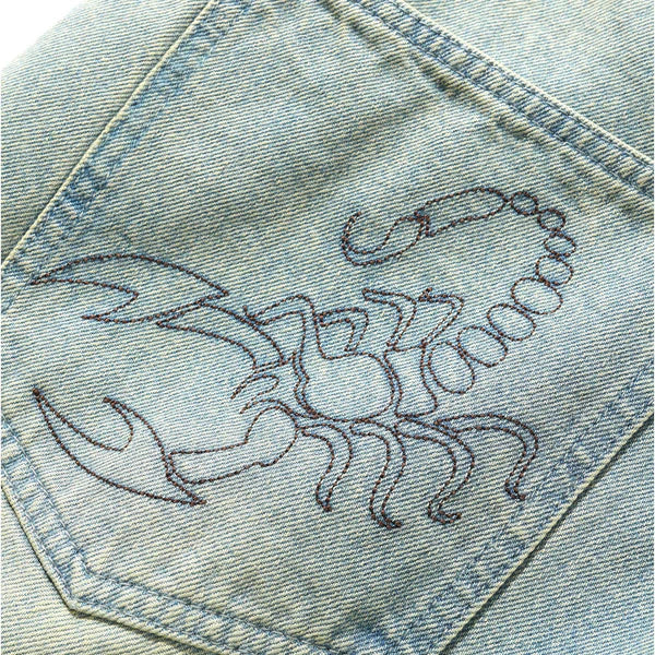 Embroidered scorpion design on denim fabric