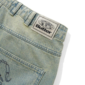 Close-up of a denim fabric with a 'Butter' brand label on a white background