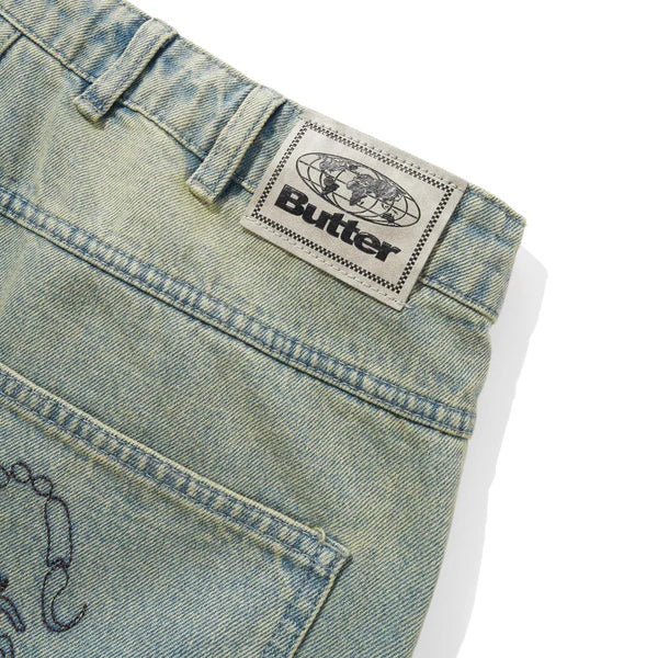 Close-up of a denim fabric with a 'Butter' brand label on a white background