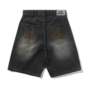 Black denim shorts with embroidered designs on the back pockets, displayed against a white background.