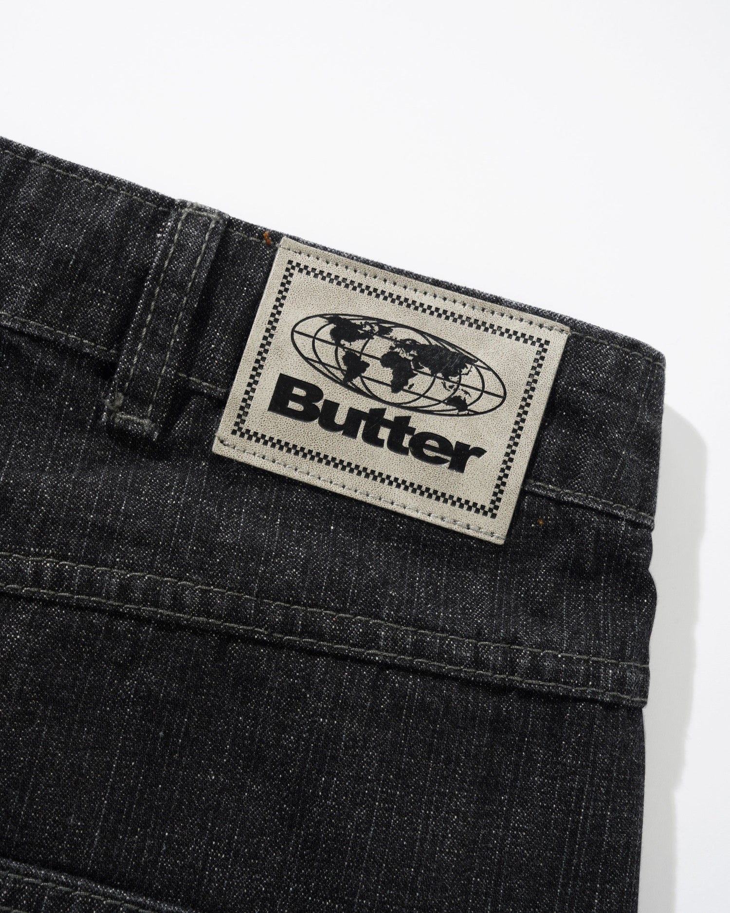 Black denim jeans with a 'Butter' brand label on a white background