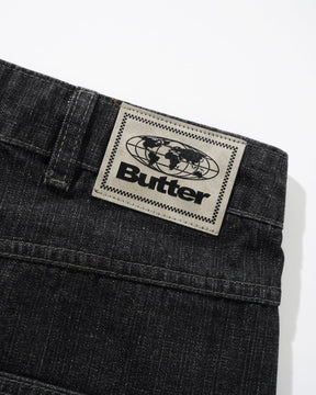 Black denim jeans with a 'Butter' brand label on a white background