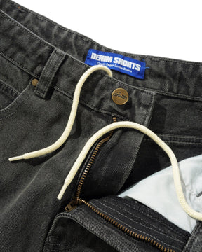 Close-up of gray denim shorts with brand label and zipper detail.