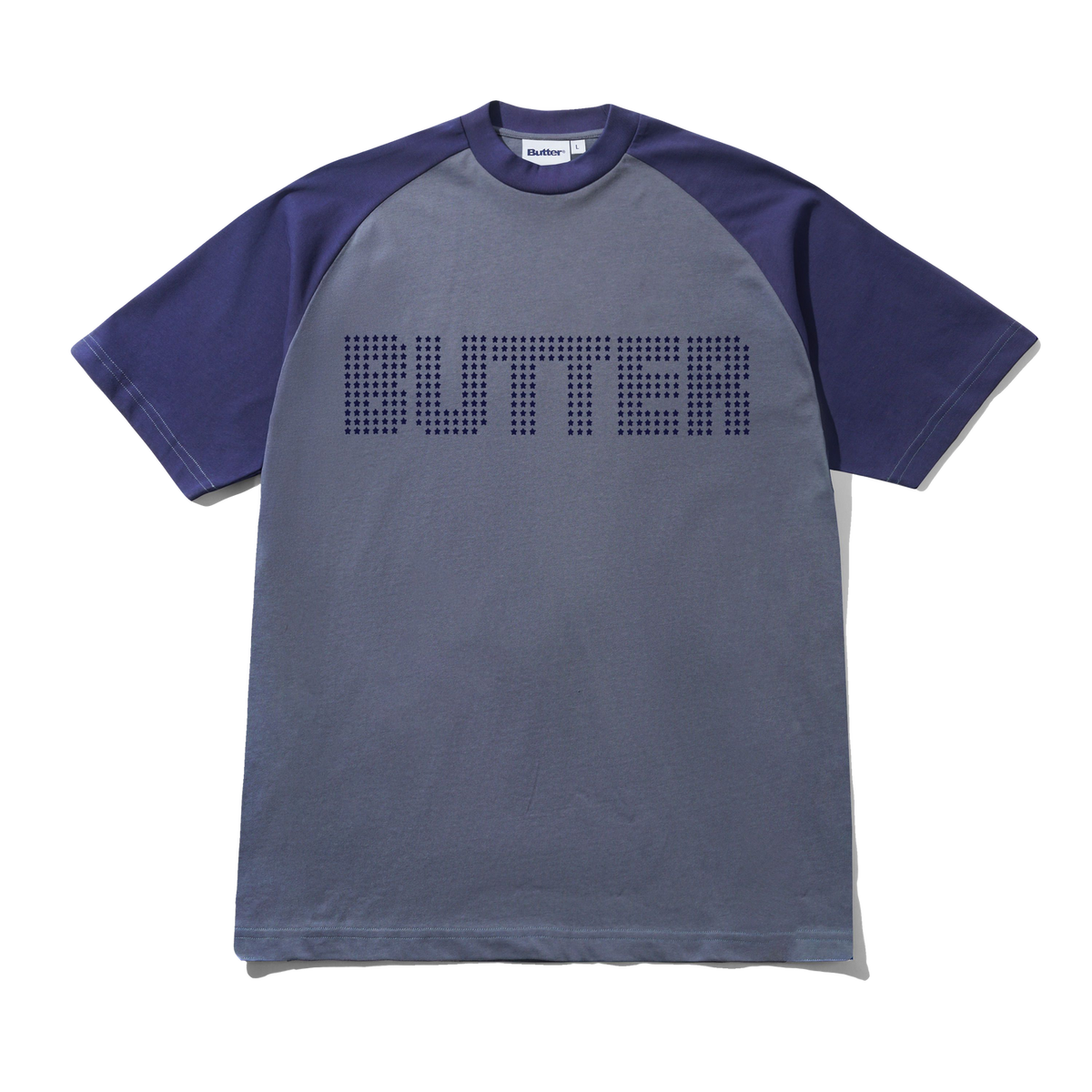 A short-sleeve raglan t-shirt with a slate blue-gray body and dark purple sleeves, featuring the word 'BUTTER' printed across the chest in a dotted pixelated font.