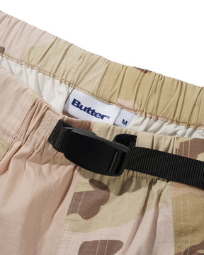 Camouflage pants with a black strap and visible 'Butter' brand label on a white background
