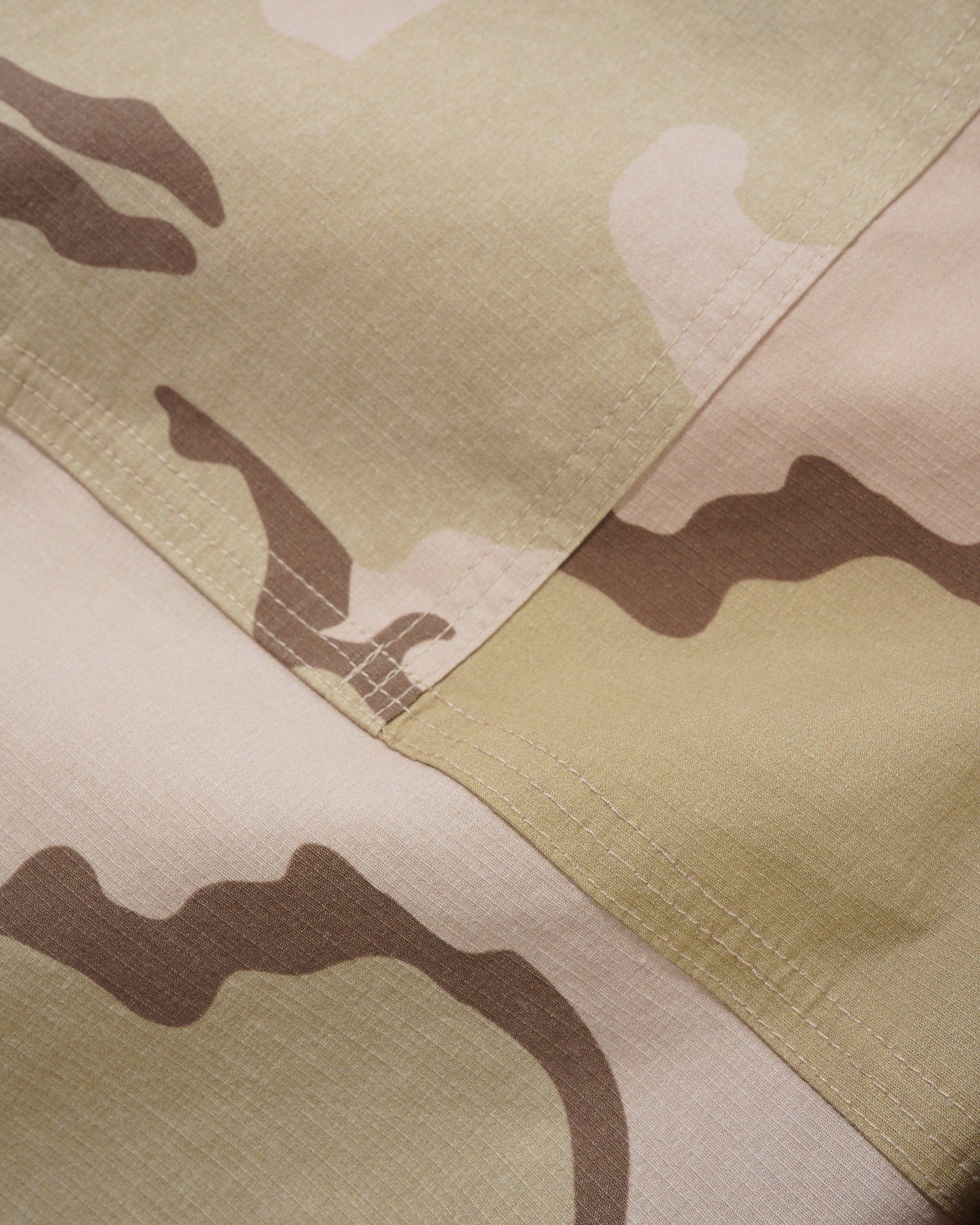 Close-up of a camouflage pattern fabric with shades of green, brown, and beige.