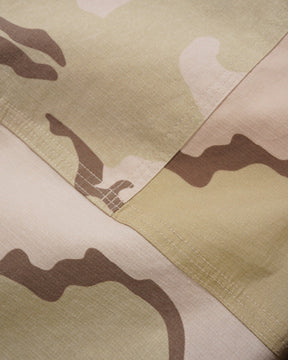 Close-up of a camouflage pattern fabric with shades of green, brown, and beige.