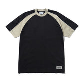 A short-sleeve raglan t-shirt in black and beige, featuring a black body and sleeves with beige shoulder panels and collar trim, laid flat on a white background.