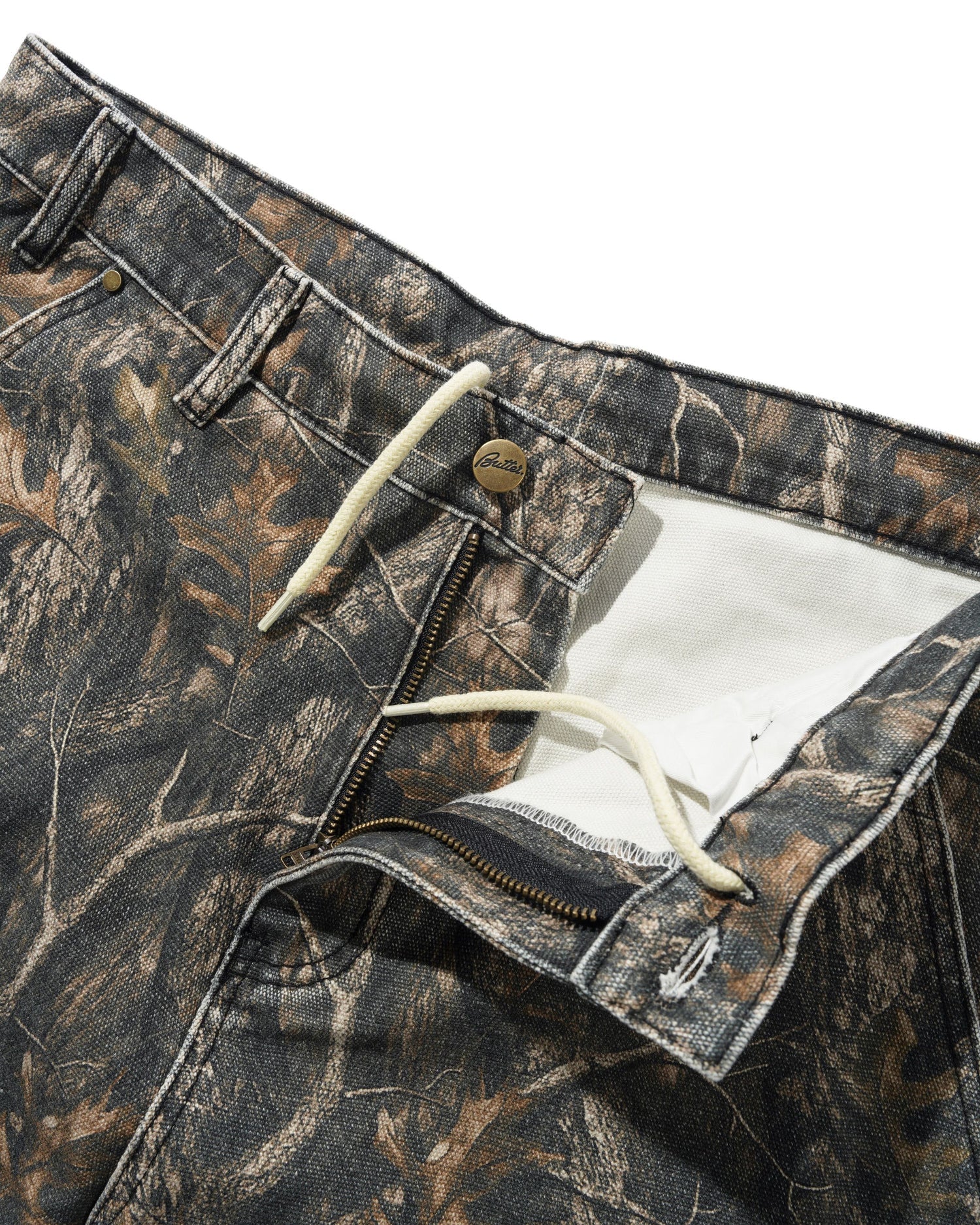 Close-up of camouflage pants with a zipper and button detail on a white background
